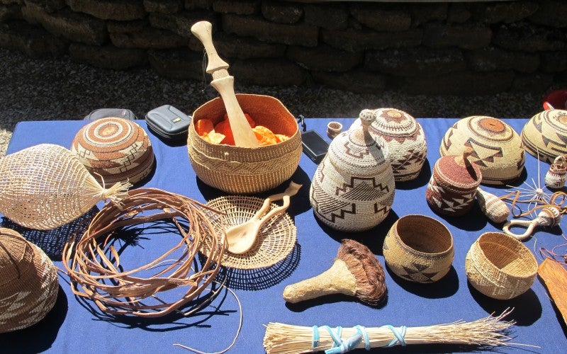 An assortment of hand-woven baskets and goods laid out on a blue tablecloth. 