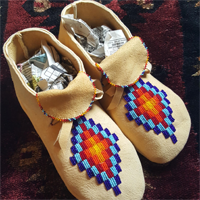 Light tan moccasins with beaded diamond design in blue, red, orange, and yellow beads.