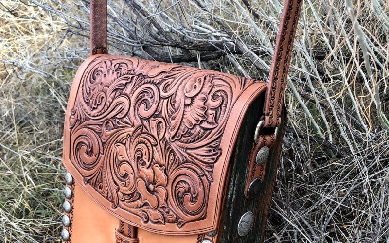 A brown leather handbag with intricate details on the front flap.