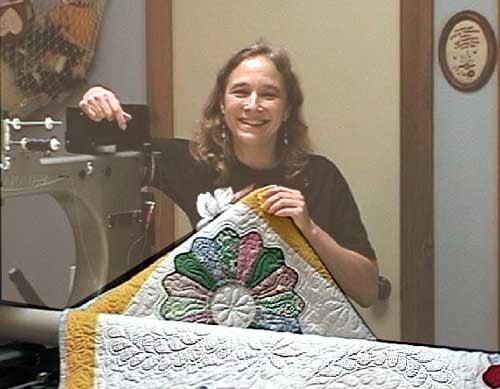 Lisa Taylor posing with a quilt at her sewing machine.