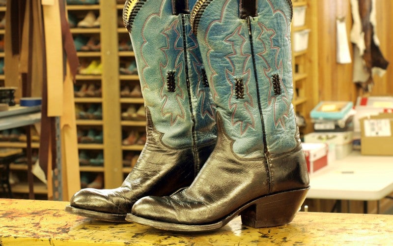 A pair of black and blue Western cowboy boots sit on a counter.