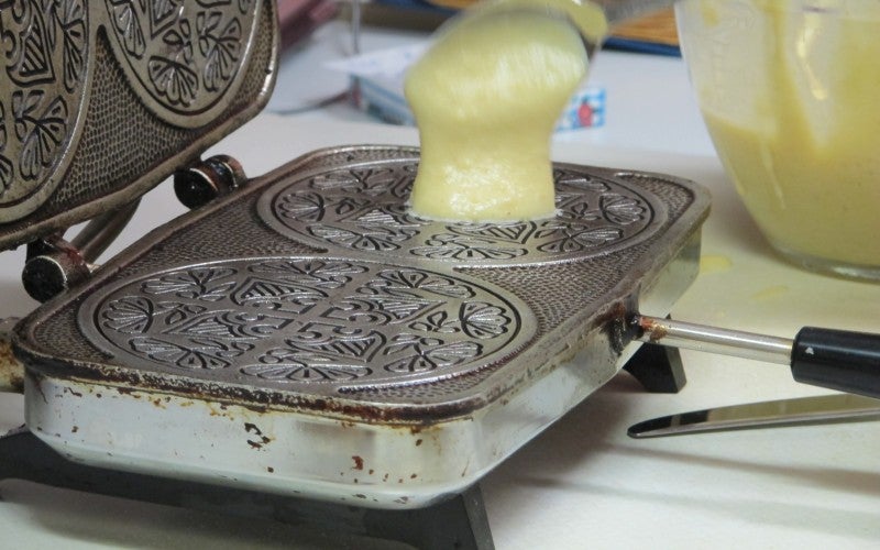 Lefse dough is spooned onto a metal iron.
