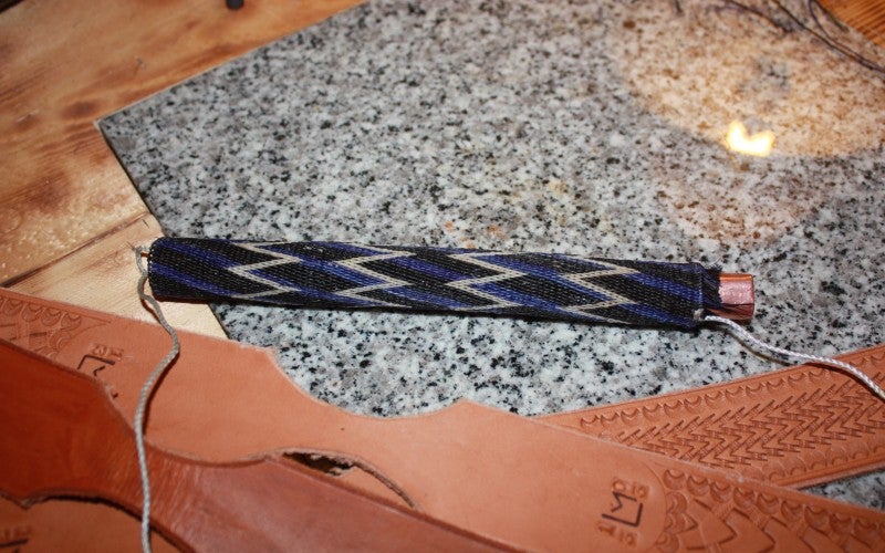 Rawhide braided band with a background of black and blue diagonal stripes with an overlaid pattern of white zigzags.