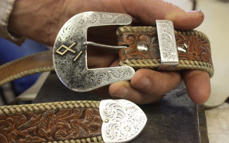 A handcrafted dark brown belt with flower engravings and a silver buckle containing a rune emblem.
