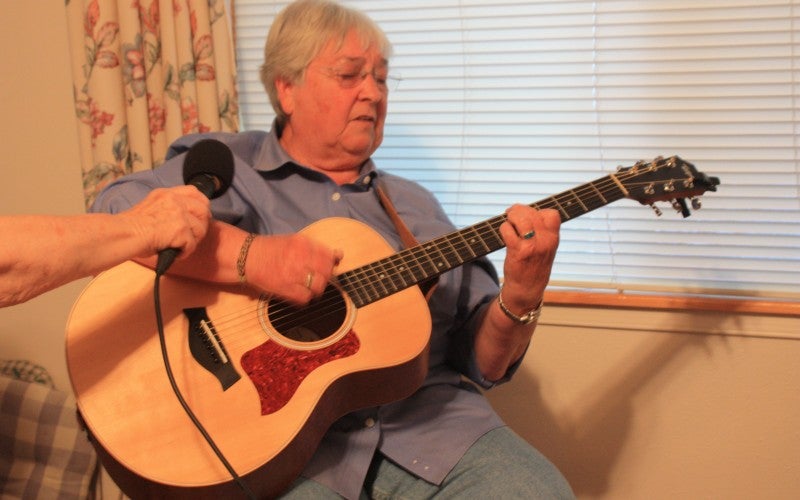 Terry plays a guitar and wears a blue shirt.