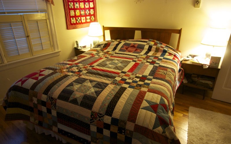 A multi-colored bed quilt of geometric design.