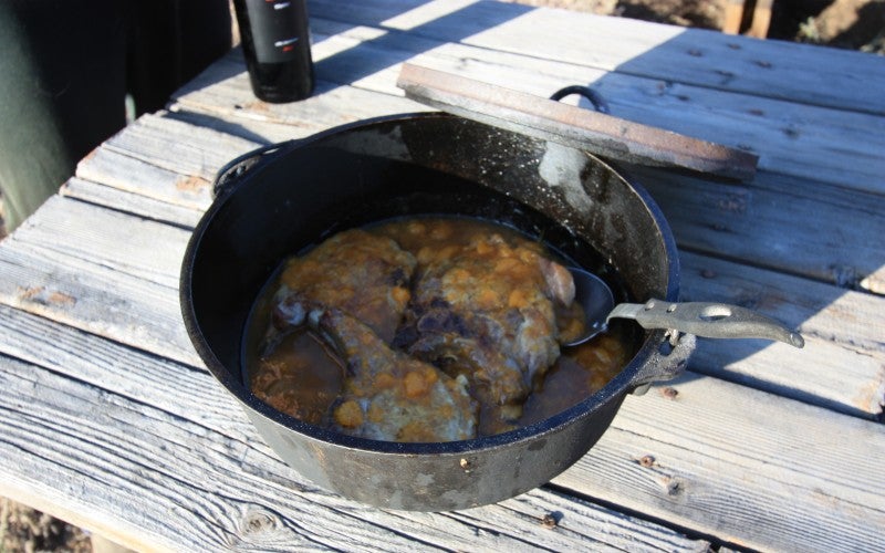 Cooked porkchops in a metal pot on a picnic table