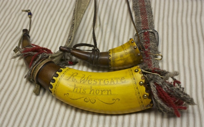 Two powder horns with yellow labels reading "R. Westgate - his horn."