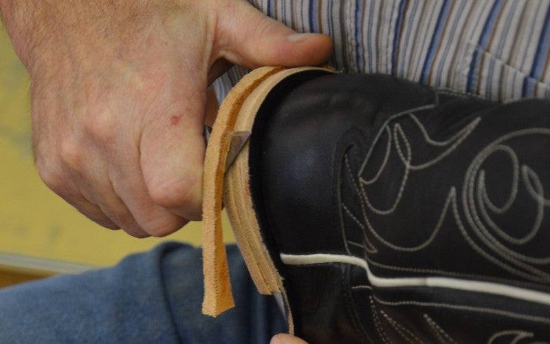 Richard Stapleman cuts excess leather off the heel of a black leather boot