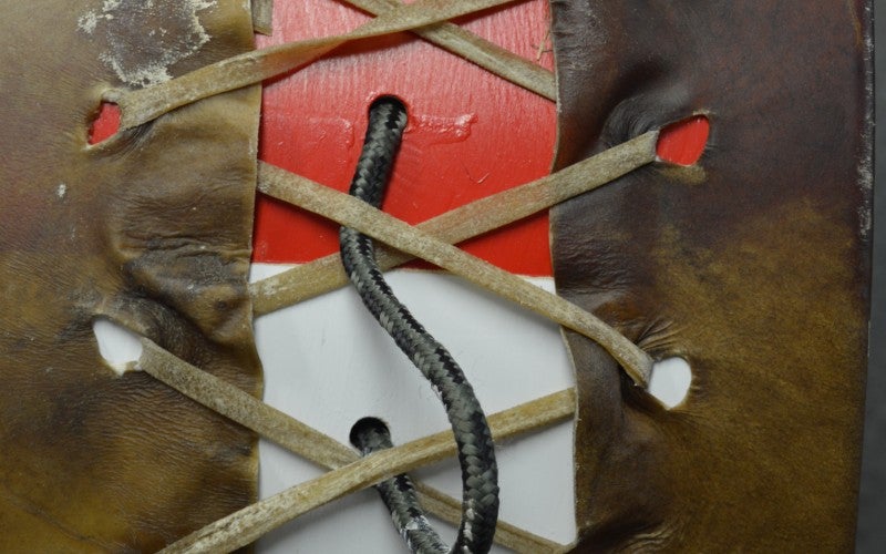 The leather pieces of a drum tied together with rope.