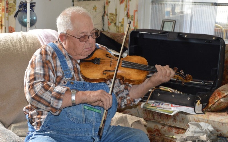 Robert plays violin in an armchair