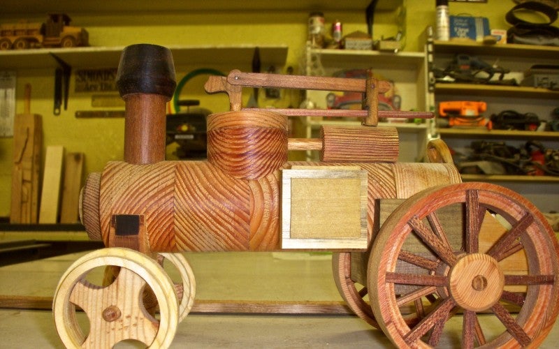 A small farm vehicle replica made from wood.