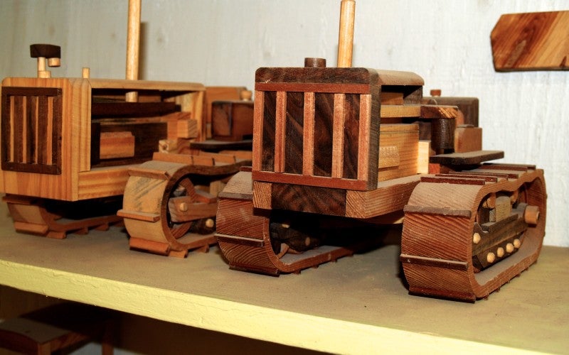 Two small tractor replicas made from wood.