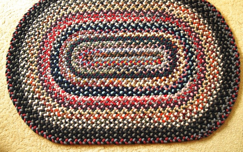 A brown, red, and tan oval-shaped braided rug.