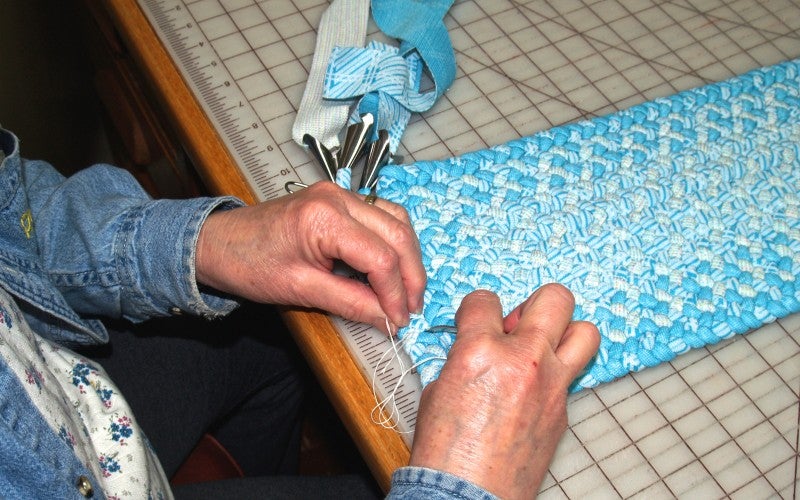 Judi braids a small light blue and white rug.