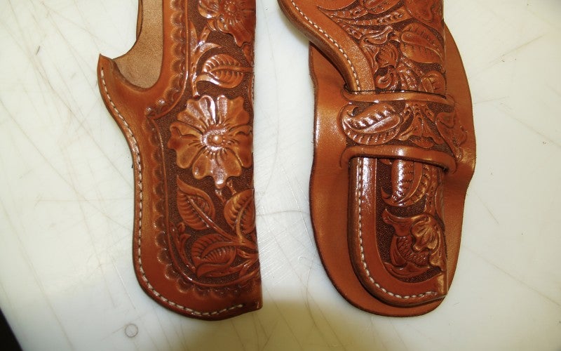 Close-up image of two leather gun holsters detailed with flower designs.