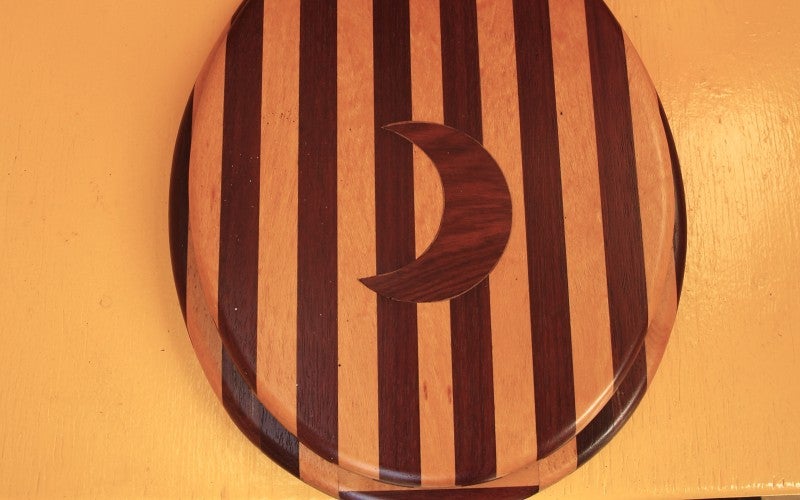 A striped wooden toilet seat with a crescent moon in the center