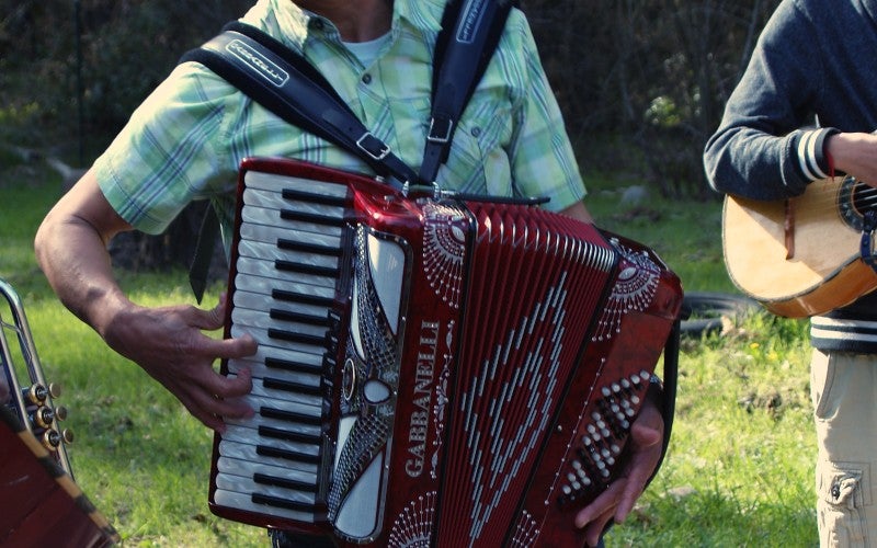 A man plays a red accordion outside.