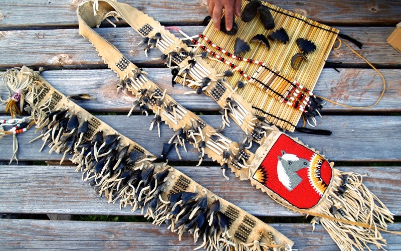 Various items including a small tule mat, deer hooves, and a small tan and red bag with a horse design.