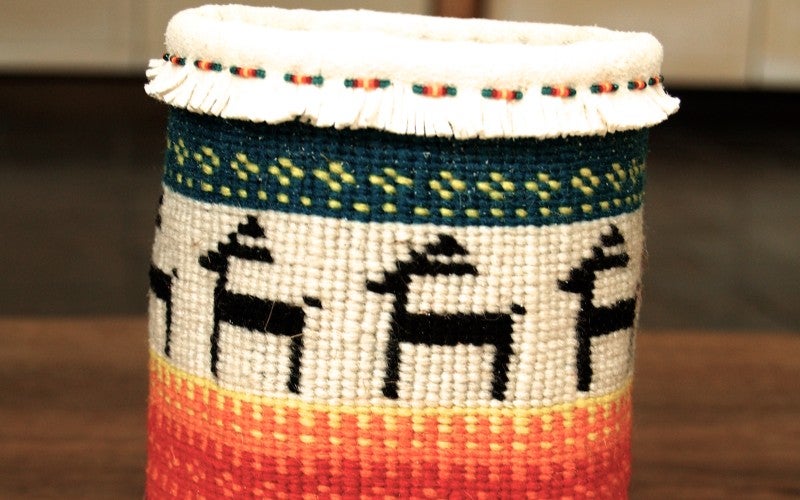 A blue, red, orange, yellow, white, and green woven basket featuring minimalist animal imagery.