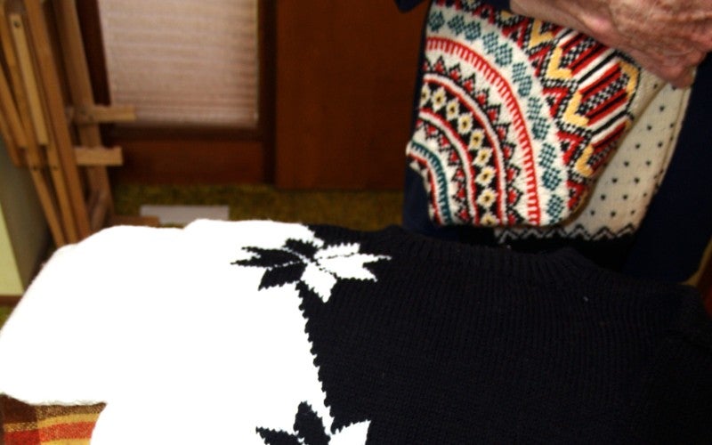 A black and white knitted shirt with three stars placed vertically in the center.