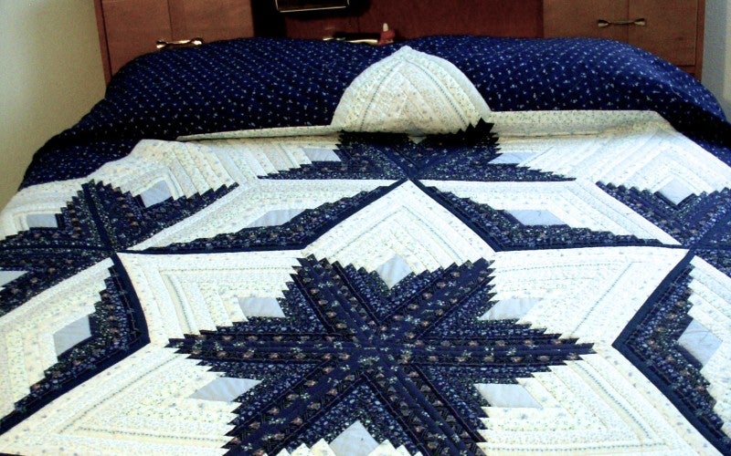 A white and blue quilt with a star pattern in the middle.