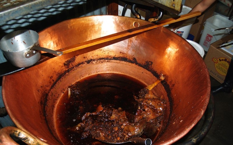 Food cooking in a large copper pot.