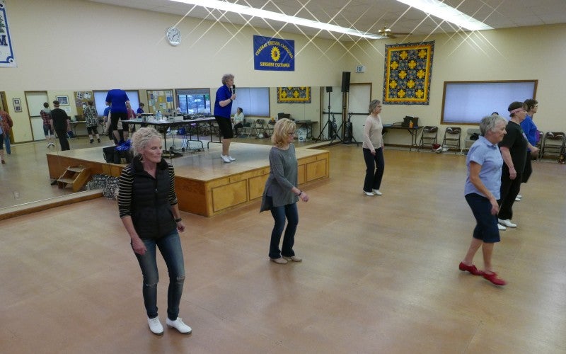 Six people in a dance studio practice clog dancing.