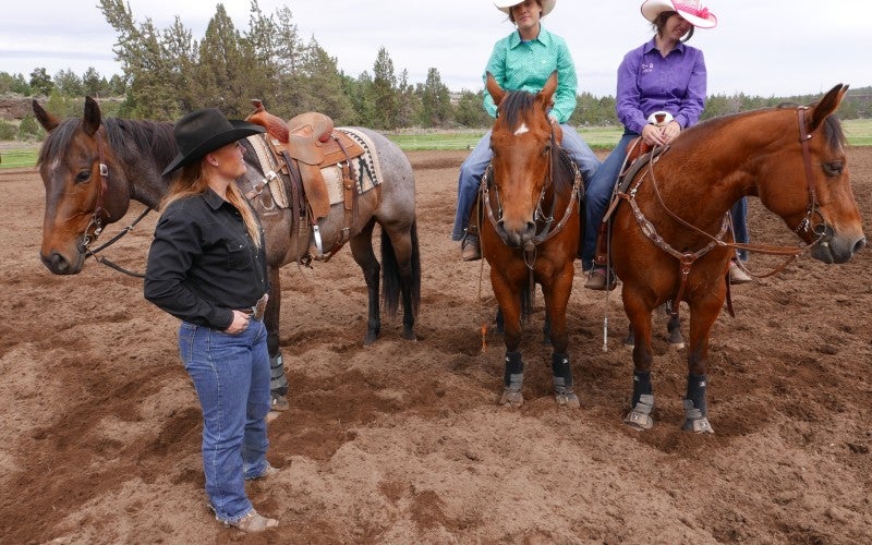 Tonya talks to two women while they sit on brown horses