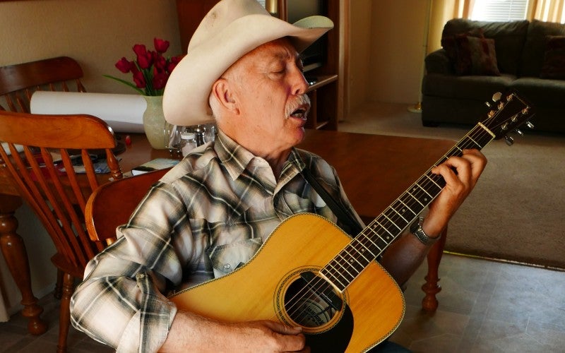 Close-up of Lonny singing while playing the guitar.