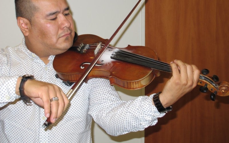 Jose plays a violin, wearing a white shirt.
