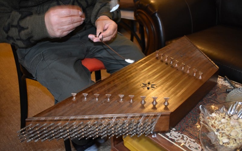 Jamshid plays a wooden santur instrument.