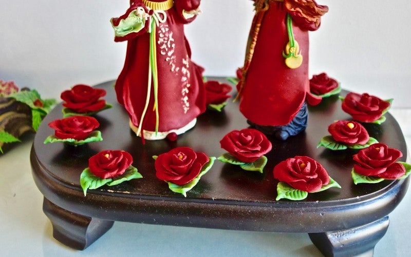 A sculpture depicting two people in red dresses with roses circling them.