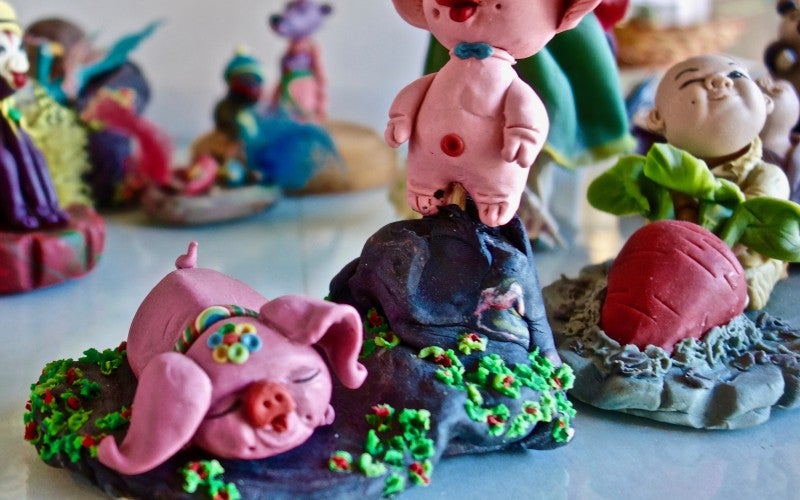 A sculpture depicting two pink pigs sitting on a rock.