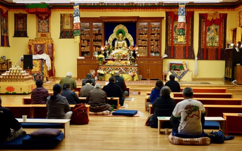 A group of people sit together in front of a buddhist shrine