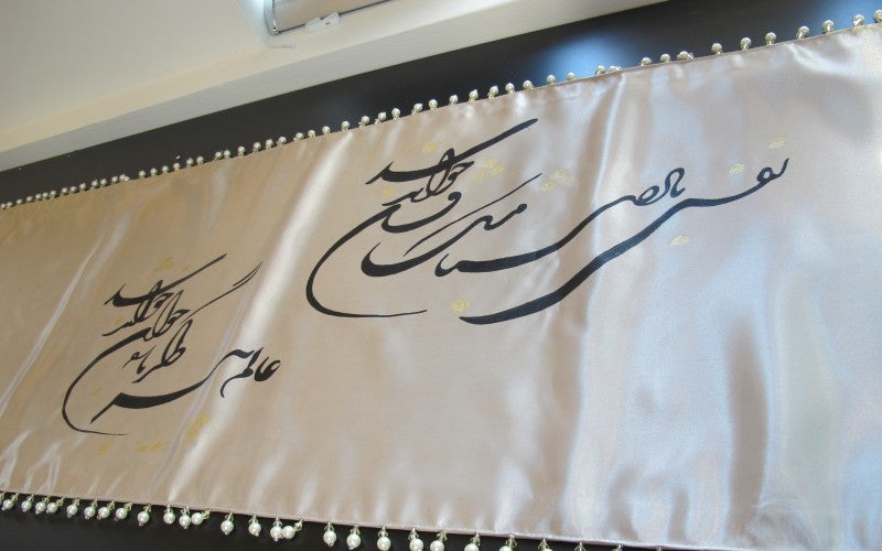 A white tapestry with black calligraphy designs.