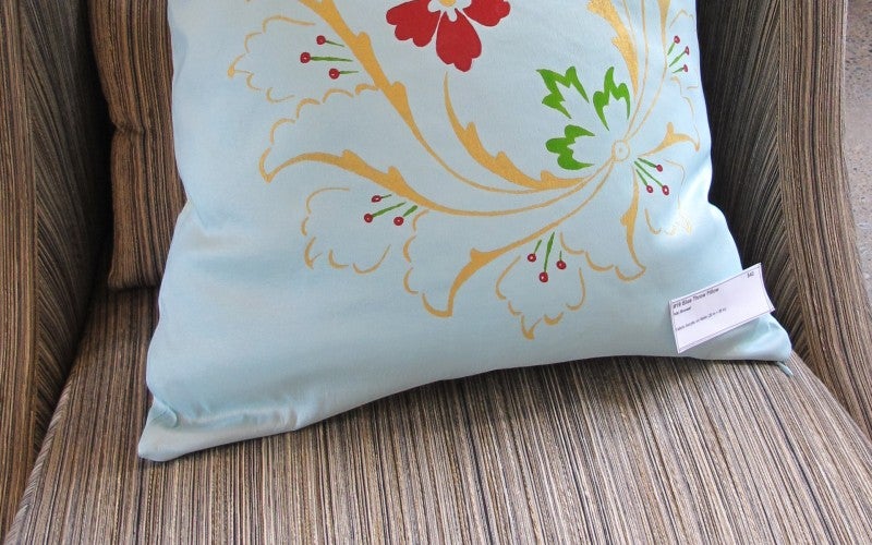 A white pillow with a red, yellow, and green flower design.