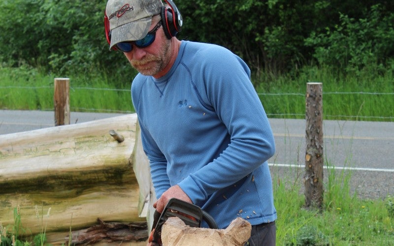 James carving a piece of wood with a chainsaw.