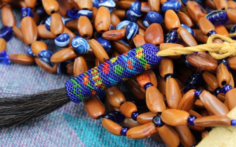 A beaded leather piece rests on wooden beads