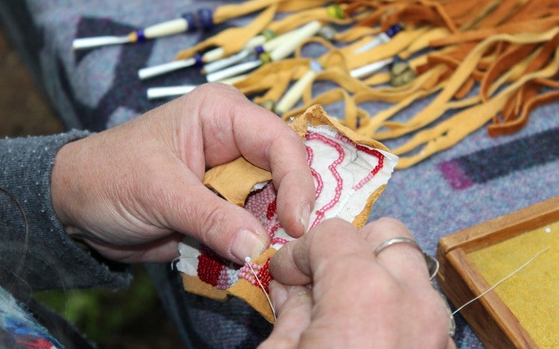 Teresa works on a piece of beaded leather