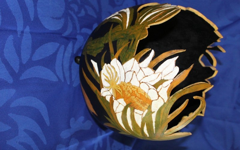 carved bowl with white flowers and green grass painted on the sides.