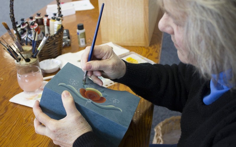 Meshnik paints a blue box in the rosemåling style