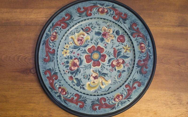 An ornatee rosemåling style painted blue plate
