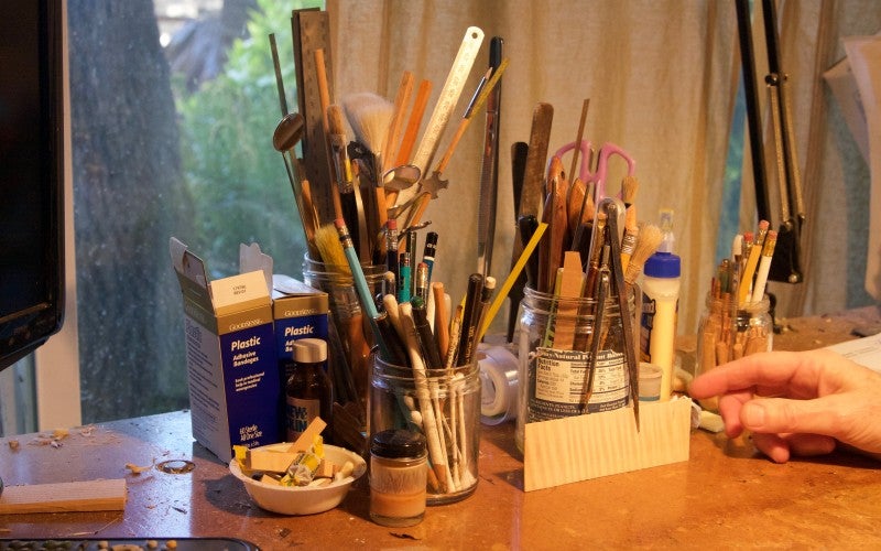 Jars of instrument-making tools, including rulers, pencils, and scissors.