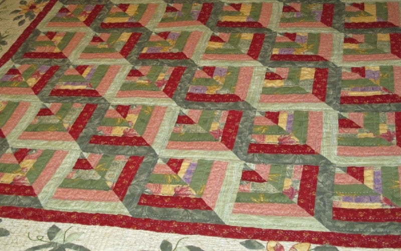 A green, pink, and red zig-zag patterned quilt.