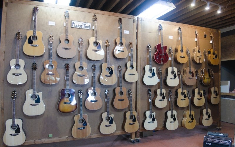 Multiple guitars hanging on a wall partition. 