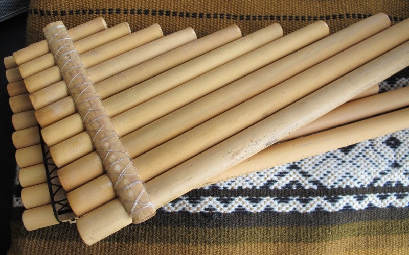 Two sets of wooden pipes rest on a brown woven blanket.