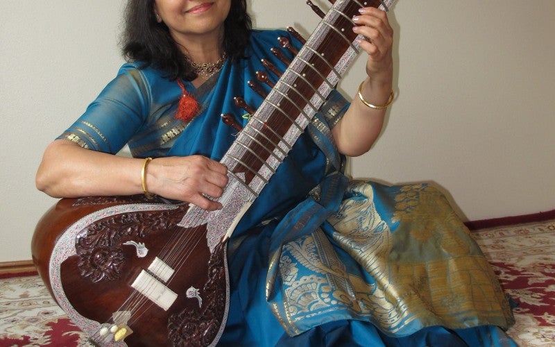 Nisha Joshi sits with an Indian classical instrument