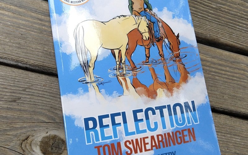 A blue book titled "Reflection: Cowboy Poetry" by Tom Swearingen