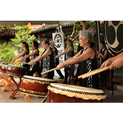 A group of people play wide taiko drums